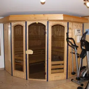 Raum mit Fitnessgeräten und Sauna aus hellem Holz
